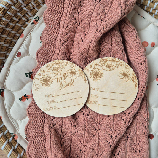 Two wooden discs with floral designs on a pink knitted fabric background